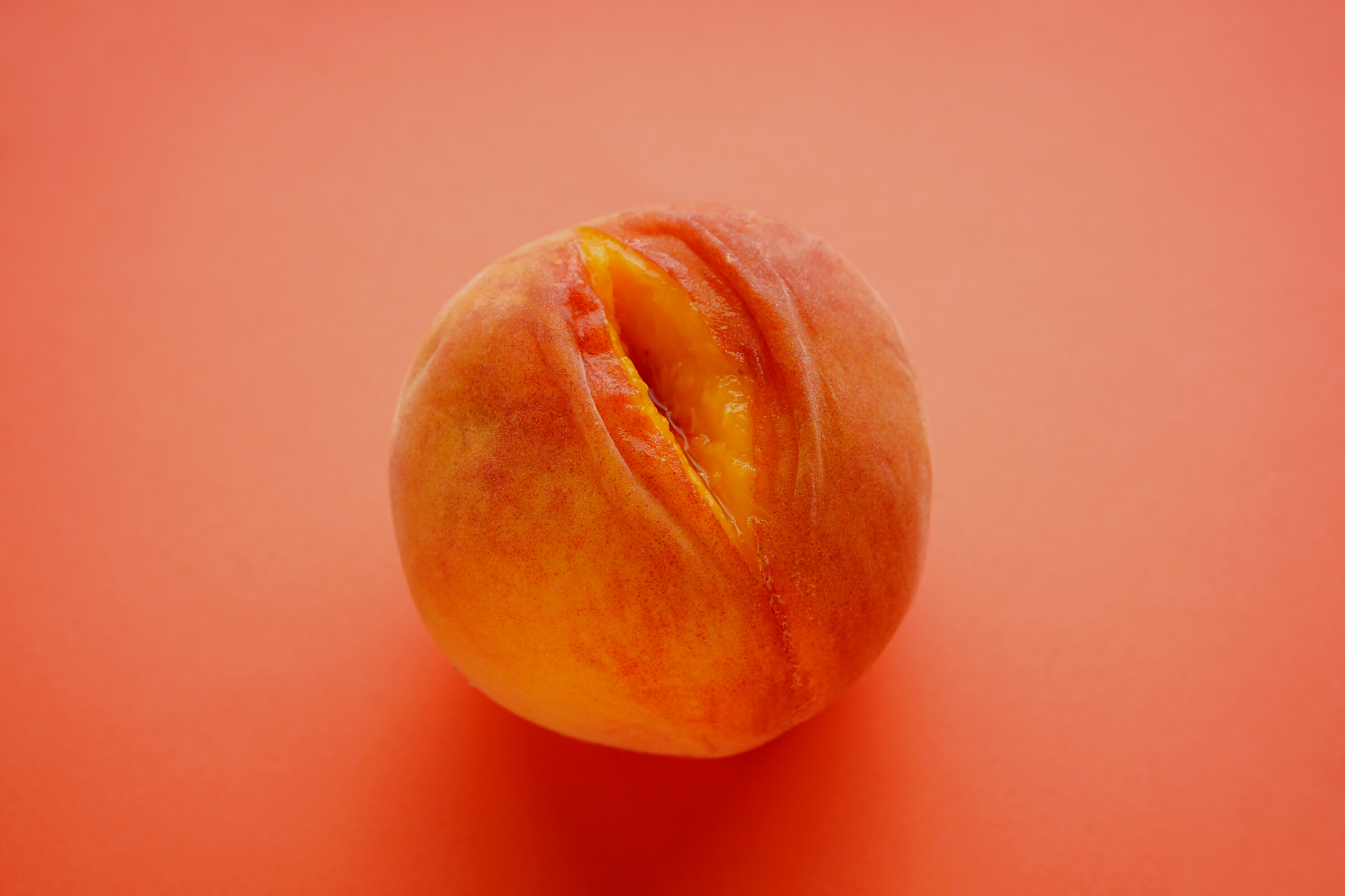 Juicy peach on a orange background. Sex concept